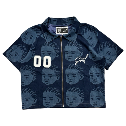 A short-sleeved collared shirt with a repeating pattern of baby faces and ’00’’ on the left chest, and ’Söül’ on the right chest, with a front zipper closure.
