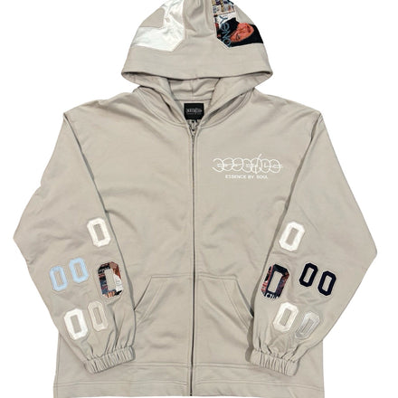 A light beige zip-up hoodie with patched details and numbers on the sleeves.